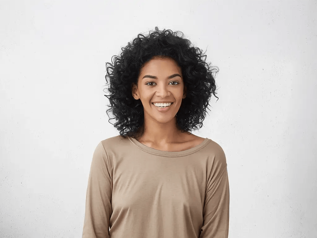 cheerful young woman with curly hair posing in studio with happy smile